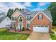 Two-story brick and siding home featuring a two-car garage, manicured lawn, front porch swing, and solar panels at 8913 Walking Stick Trl, Raleigh, NC 27615