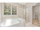 Bright bathroom with a glass door shower and a large soaking tub at 9308 Carisbrook Ct, Raleigh, NC 27615