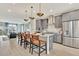 Spacious kitchen with sleek gray cabinets, stainless steel appliances, island seating, and modern pendant lights at 10011 Secluded Gdn Dr # 169, Apex, NC 27523