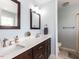 Bright bathroom featuring double sinks, a quartz countertop, and wood cabinetry and an open shower at 1100 Open Field Dr, Garner, NC 27529