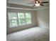 Well-lit bedroom featuring plush carpeting, ceiling fan, tray ceiling and three large windows providing natural light at 112 Briarfield Dr, Apex, NC 27502