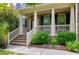Inviting covered front porch with brick stairs, white railings, columns, and manicured landscaping at 112 Briarfield Dr, Apex, NC 27502
