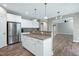 Open kitchen featuring stainless steel refrigerator, wood floors, white cabinetry and view to living space at 112 Briarfield Dr, Apex, NC 27502