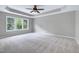 Spacious primary bedroom with a ceiling fan, large window, and plush carpeting for comfort and relaxation at 112 Briarfield Dr, Apex, NC 27502