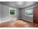 Bedroom with hardwood floors, two windows allowing natural light, and neutral gray walls at 1219 Lakeland St, Durham, NC 27701