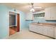 Charming kitchen with light blue walls, white cabinetry, a ceiling fan, and an adjoining dining room at 1219 Lakeland St, Durham, NC 27701