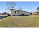 Lush backyard with green lawn showcases a white brick building featuring multiple windows and mature trees at 1246 Nc-27, Benson, NC 27504