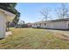 Backyard view showcasing a sprawling green lawn, white building and neighboring homes under a clear blue sky at 1246 Nc-27, Benson, NC 27504