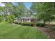 Exterior view of a home featuring a lush green lawn, mature trees, and a charming wooden deck at 132 Edgewood Dr, Louisburg, NC 27549