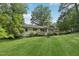 Expansive backyard showcasing a well-maintained lawn, mature trees, and the home's exterior with a wood deck at 132 Edgewood Dr, Louisburg, NC 27549