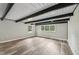 Bright empty room with hardwood floors, dark wood ceiling beams, and many windows allowing lots of natural light at 132 Edgewood Dr, Louisburg, NC 27549