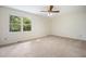 Empty bedroom with a ceiling fan, carpeted floor, and a large window overlooking the trees at 1600 Budwood Dr, Raleigh, NC 27609