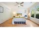 Bright bedroom with ceiling fan, double closets, and a large window overlooking the outdoor landscape at 1600 Budwood Dr, Raleigh, NC 27609