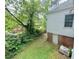 Side yard with mature trees and partial views of the house exterior at 1609 Cypress Dr, Henderson, NC 27536
