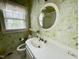 Cozy bathroom featuring floral wallpaper, an oval mirror, and a vanity with a white sink at 1609 Cypress Dr, Henderson, NC 27536