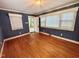 Cozy bedroom with hardwood floors, blue walls, and natural light from multiple windows at 1609 Cypress Dr, Henderson, NC 27536
