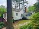 Exterior view of the rear of the home with white siding and mature trees at 1609 Cypress Dr, Henderson, NC 27536