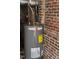 Hot water heater in a basement or utility area with exposed brick walls at 1609 Cypress Dr, Henderson, NC 27536