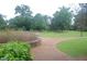 Curving walkway in the garden with grass, trees, and plantings at 1908 Smallwood Dr, Raleigh, NC 27605