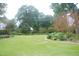A grassy yard with garden plots and trees in the background at 1908 Smallwood Dr, Raleigh, NC 27605