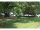 Wide view of a lush green front yard with mature shade trees on a sunny day at 1908 Smallwood Dr, Raleigh, NC 27605
