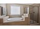 Bright bathroom featuring a soaking tub with tiled surround, a window, and a glass enclosed shower stall at 2100 Della Ct, Apex, NC 27502