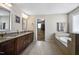 Elegant bathroom with a double vanity, granite countertop, soaking tub, and doorway to walk in closet at 2100 Della Ct, Apex, NC 27502