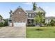 Beautiful two-story brick home with a manicured lawn and three-car garage on a sunny day at 2100 Della Ct, Apex, NC 27502