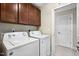 Convenient laundry room with white washer and dryer, tile flooring, and overhead cabinet storage at 2100 Della Ct, Apex, NC 27502