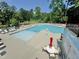 Large community pool surrounded by lounge chairs, umbrellas, and trees, perfect for relaxation and recreation at 2100 Della Ct, Apex, NC 27502
