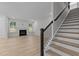 Open-concept living room with stairs, fireplace, and large windows bringing in natural light at 2329 Field Poppy Dr, Apex, NC 27502