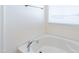 Close-up of a pristine white soaking tub with chrome fixtures beneath a window with blinds at 285 Johnson Ridge Way, Four Oaks, NC 27524