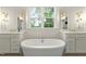 Bright bathroom featuring a soaking tub, double vanities, designer sconces, and decorative floor tiles at 3160 Mantle Ridge Dr, Apex, NC 27502