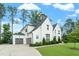 Elegant white brick home featuring a three-car garage, manicured lawn, and beautiful architectural details at 3160 Mantle Ridge Dr, Apex, NC 27502