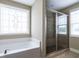 Bright bathroom boasts a soaking tub beneath decorative window and a tiled glass-door shower at 33 Northlodge Ct, Wendell, NC 27591