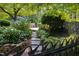 Stone path leads to brick patio with dining area, surrounded by lush garden and hydrangea bushes at 3307 Devon Rd, Durham, NC 27707