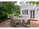 Backyard showing brick patio with dining area, grill, white brick building, and trees at 3307 Devon Rd, Durham, NC 27707