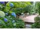 Inviting backyard featuring brick patio with dining area and lounge chairs, surrounded by lush landscaping at 3307 Devon Rd, Durham, NC 27707
