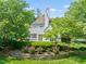 Elegant home with a manicured lawn, charming stone wall, and blooming pink roses in the garden at 3307 Devon Rd, Durham, NC 27707