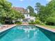 Inviting pool reflects the elegant white home, surrounded by a brick patio and green landscaping at 3307 Devon Rd, Durham, NC 27707