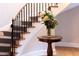 Elegant curved staircase with dark wrought iron and wood, adorned with a vase of fresh white hydrangeas at 3307 Devon Rd, Durham, NC 27707