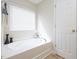Bathroom featuring a large white tub, window, and decorative vases at 3515 Mountain Brook Cir, Durham, NC 27704