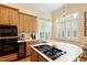 Kitchen with island cooktop, modern appliances, warm wooden cabinetry, and natural light at 3928 Bentley Bridge Rd, Raleigh, NC 27612