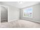 A bright bedroom with neutral carpet, a window overlooking the neighborhood, and a walk-in closet at 44 Good Morning Ln, Garner, NC 27529