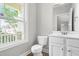 Cozy powder room featuring a window for natural light, white vanity, and a toilet at 44 Good Morning Ln, Garner, NC 27529
