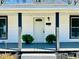 Close-up of the front porch with a white door, potted plants, and gray painted deck at 602 Dexter St, Rocky Mount, NC 27803