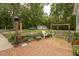 Brick patio leading to a large, treed backyard with wooden swing set and detached building at 6517 Whitted Rd, Fuquay Varina, NC 27526
