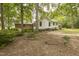 View of the home's brick and white siding and the spacious, tree-filled backyard at 6517 Whitted Rd, Fuquay Varina, NC 27526