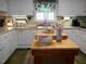 An efficient kitchen with white cabinets, laminate countertops, a dishwasher, lots of storage, and an island with a wooden countertop at 6517 Whitted Rd, Fuquay Varina, NC 27526