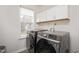 Modern laundry room with gray front load washer and dryer, cabinets, and window at 930 Pristine Ln, Rolesville, NC 27571